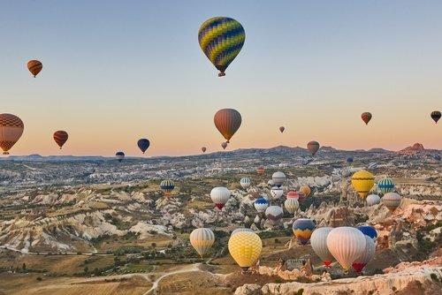 Dozens of hot-air balloons at sunrise over the rocks of Cappadocia